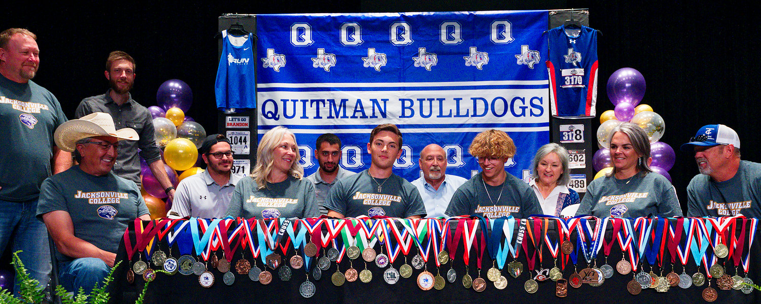 Quitman seniors Brandon Jimenez and Jack Tannebaum signed letters of intent to run track at Jacksonville College in the fall, with parents, other family and coaches from both schools on hand. Standing: Quitman athletic director Shane Webber and RJ Cowan of Run Tyler. Seated, from left, Oscar Jimenez, Jacksonville athletic director Kirby Shepherd, Chandra Jimenez, Jacksonville assistant track coach Jacob Rowland, Brandon Jimenez, Joel Tannebaum, Jack Tannebaum, Beverly Hook, Olivia Greenup and Michael Greenup. [see more signing celebrations]